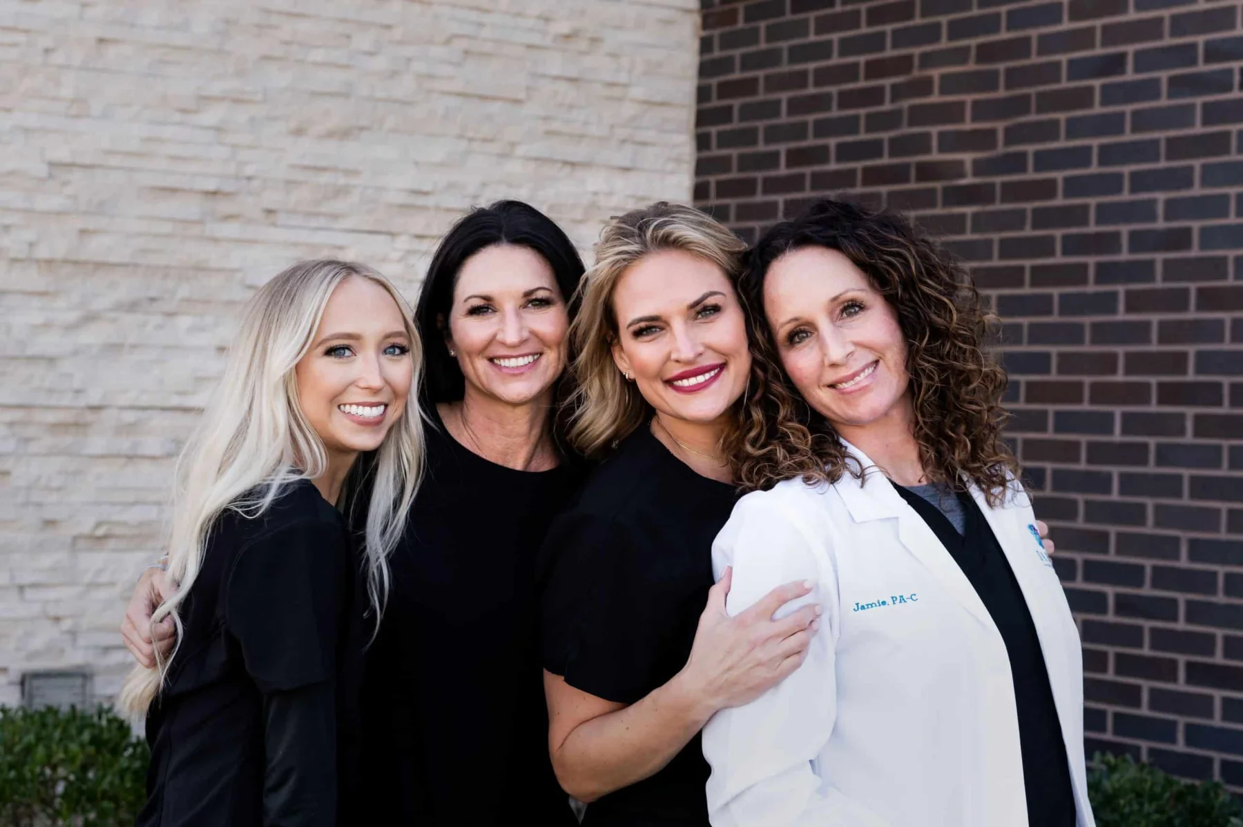 Four members of the Dahlia by WHA team, arm in arm outside the practice, one in a white coat